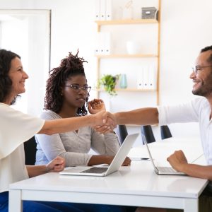 Cheerful business partners shaking hands. Confident young people reaching agreement. Agreement concept